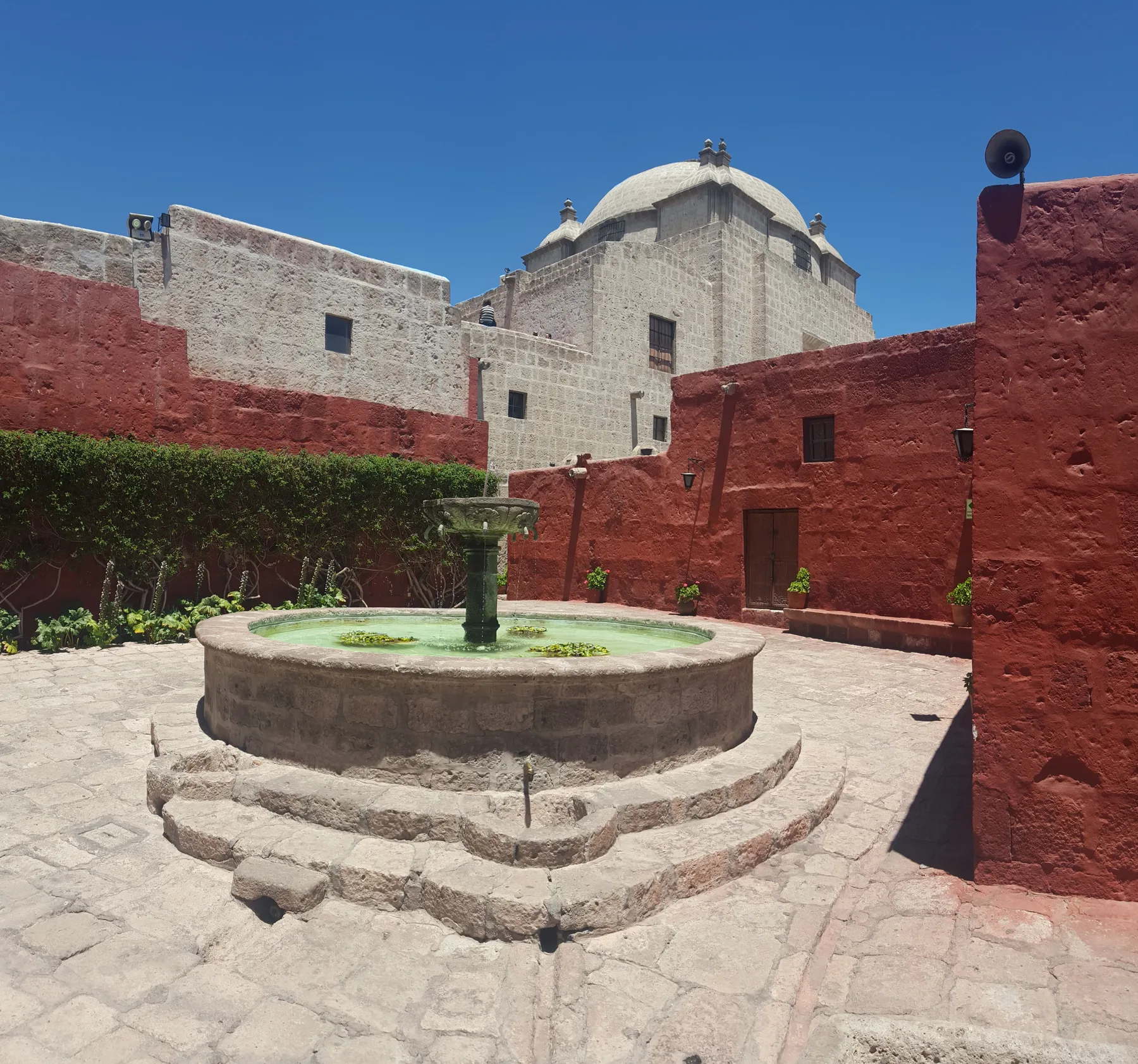 A fountain between red walls and a pale dome at Santa Catalina, Arequipa.