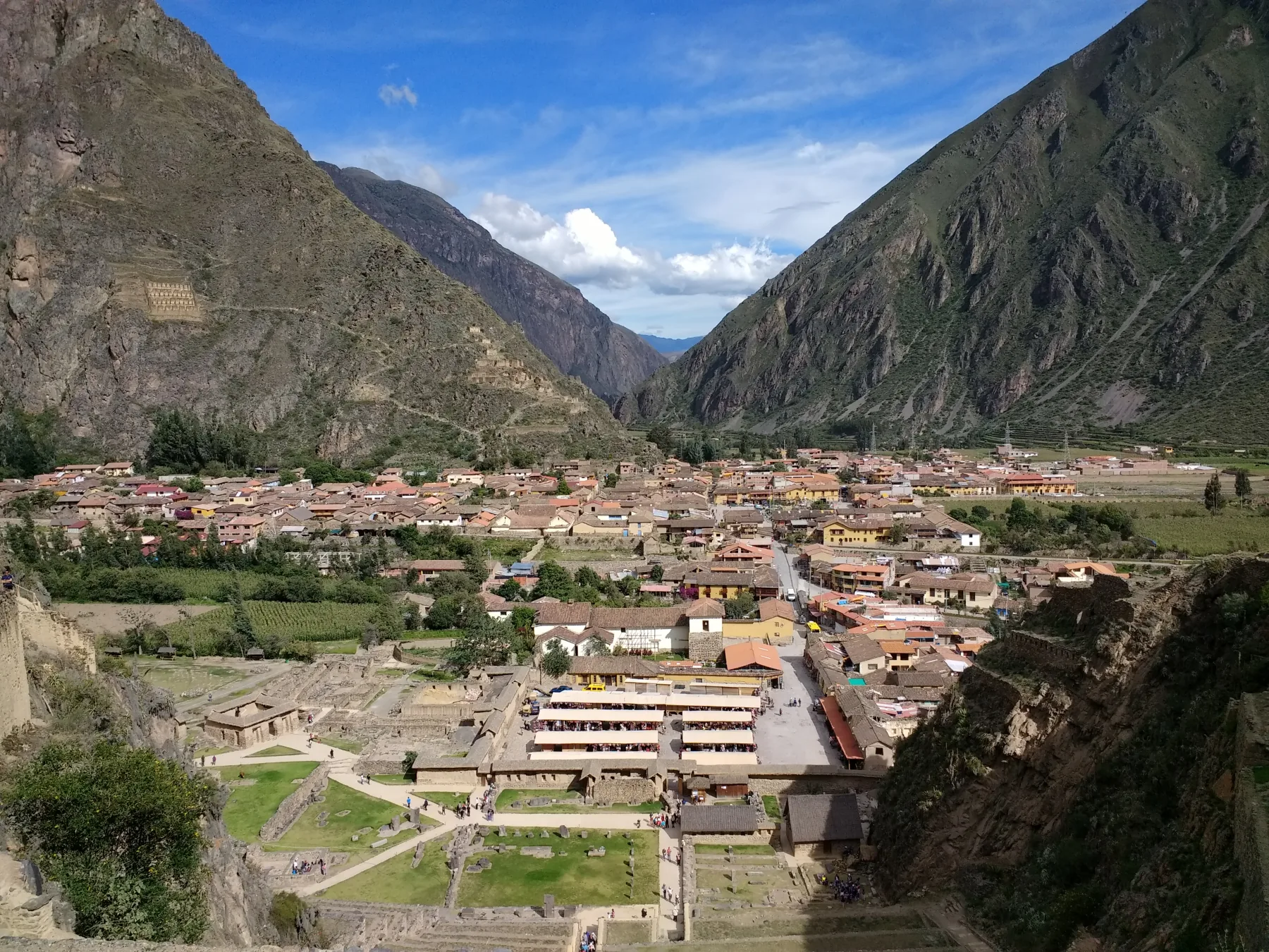 Roofs of Ollantaytambo behind stone terraces, with mountains around the town.