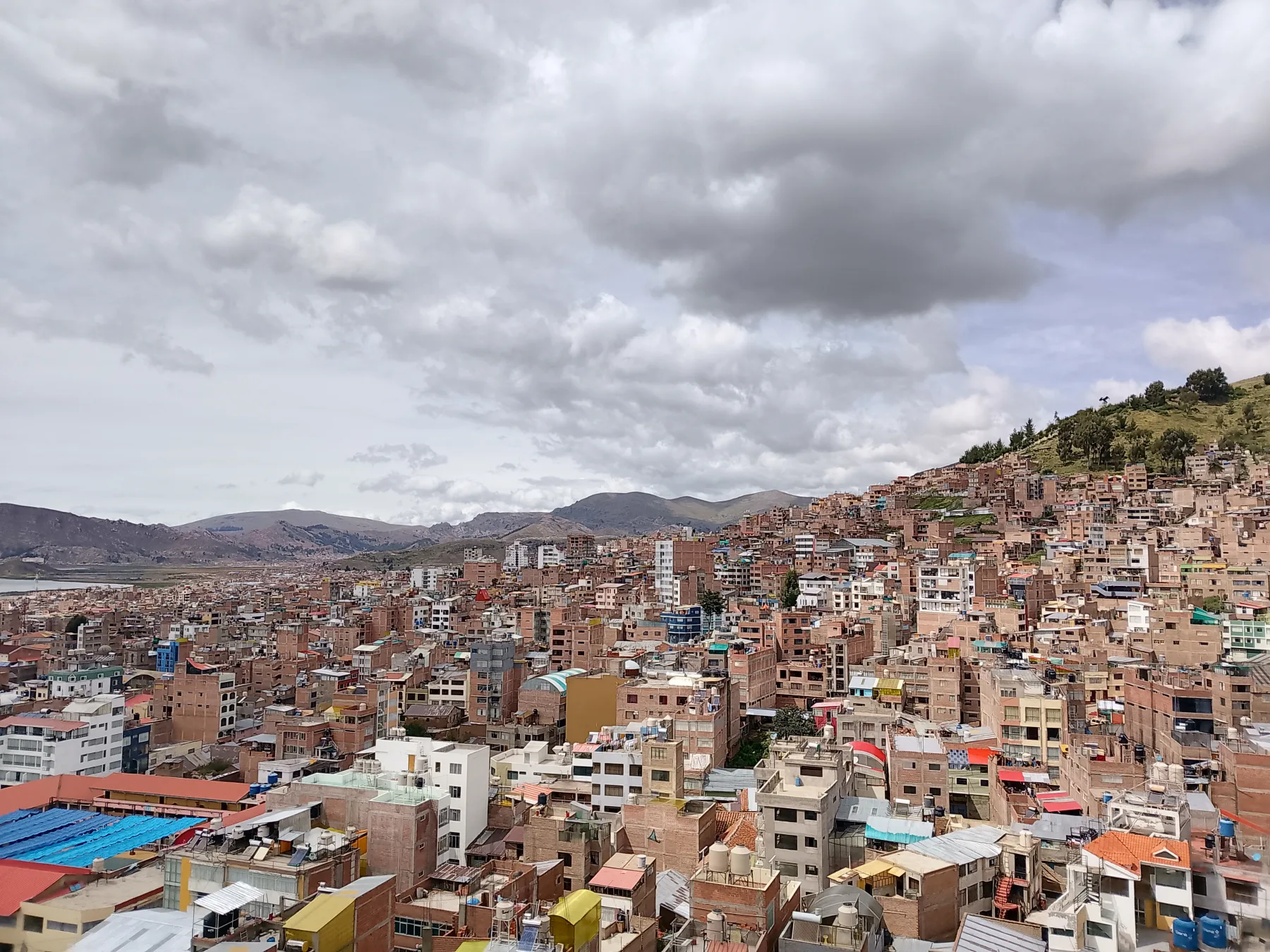 Houses on Puno's hillsides, with a narrow view of Lake Titicaca on the left, photographed in 2025.